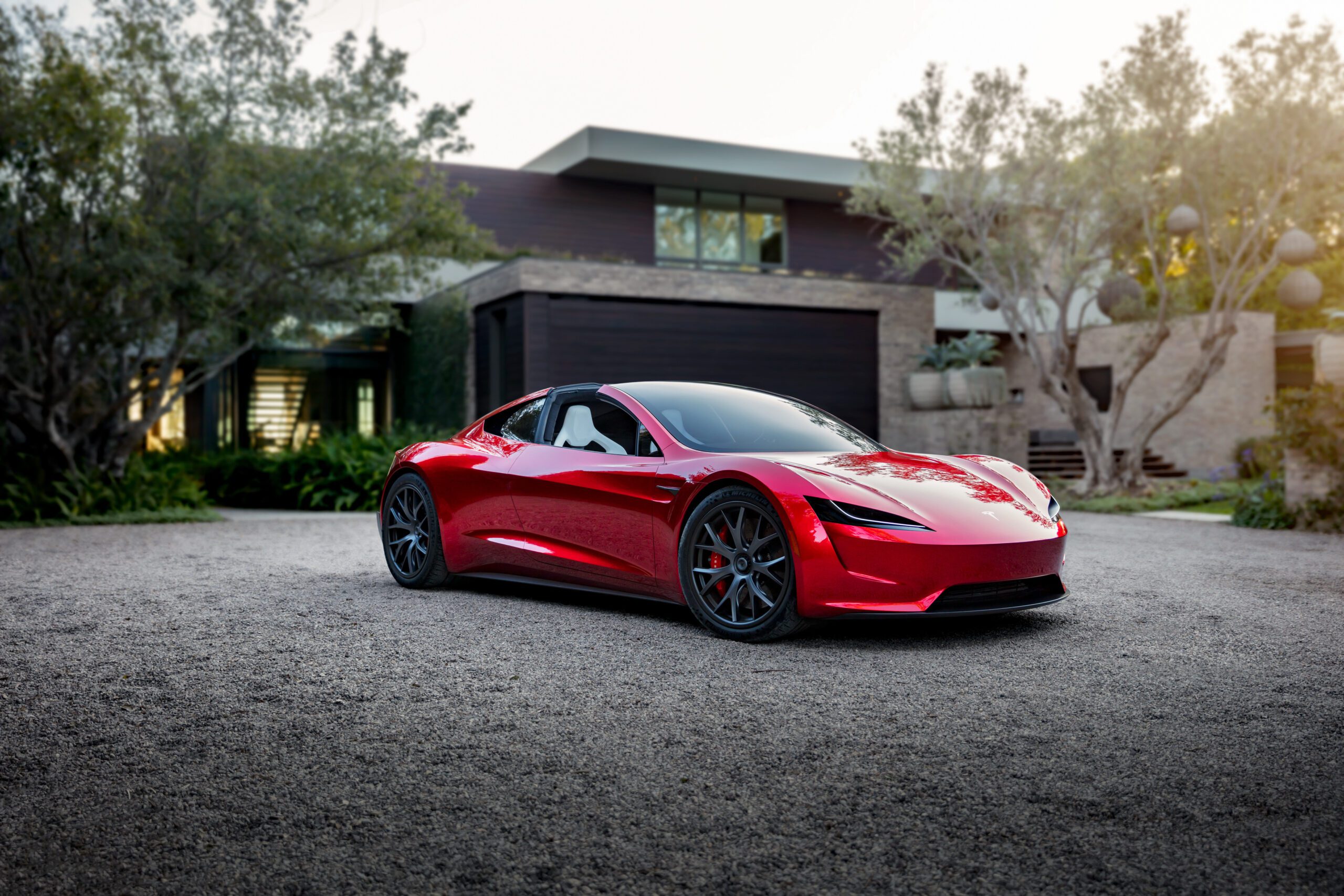 Automobil Tesla Roadster stojí na parkovisku pred luxusnou vilou